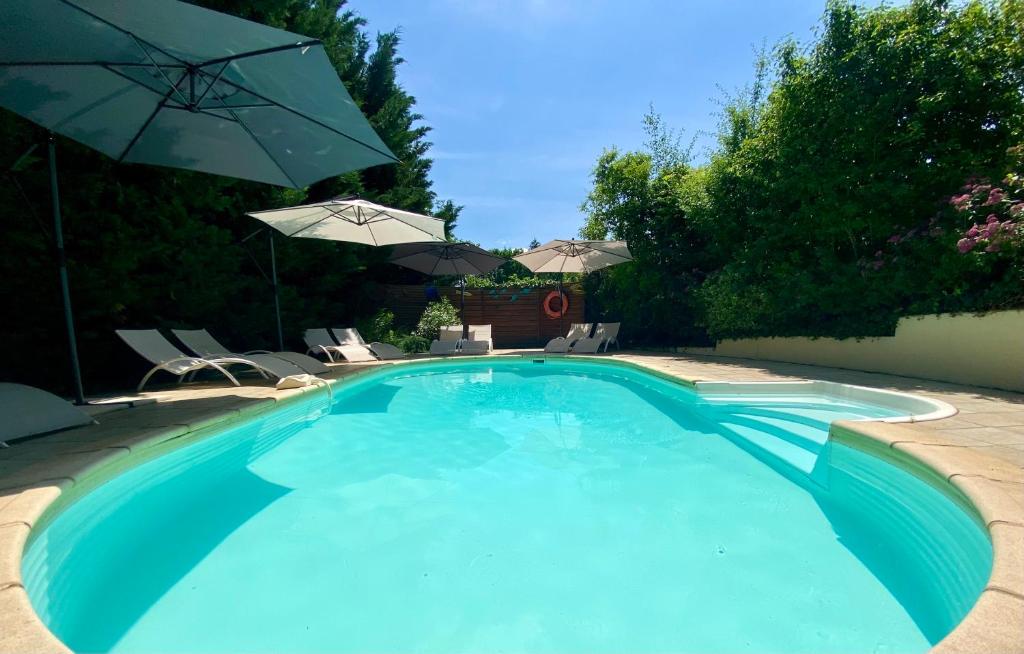 a large blue swimming pool with chairs and umbrellas at Le Petit Prince à Sarlat - Parking privé - piscine chauffée - espace bien-être Jacuzzi et massages in Sarlat-la-Canéda