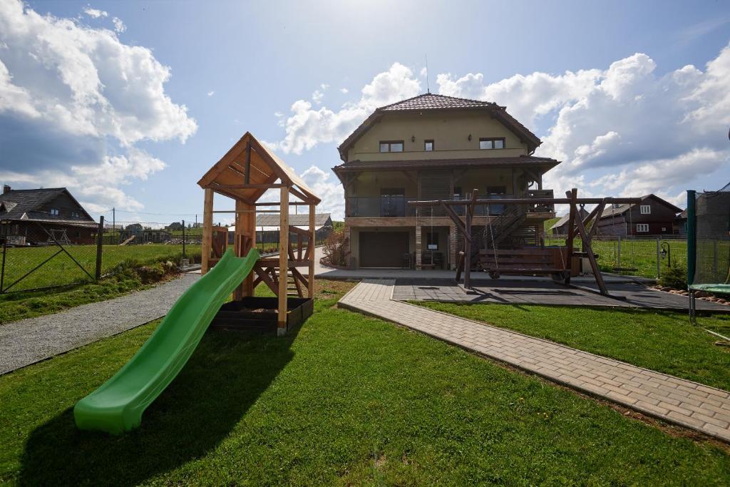 une aire de jeux en face d'une maison avec un toboggan vert dans l'établissement Grand Lake House, à Giurcuţa de Sus