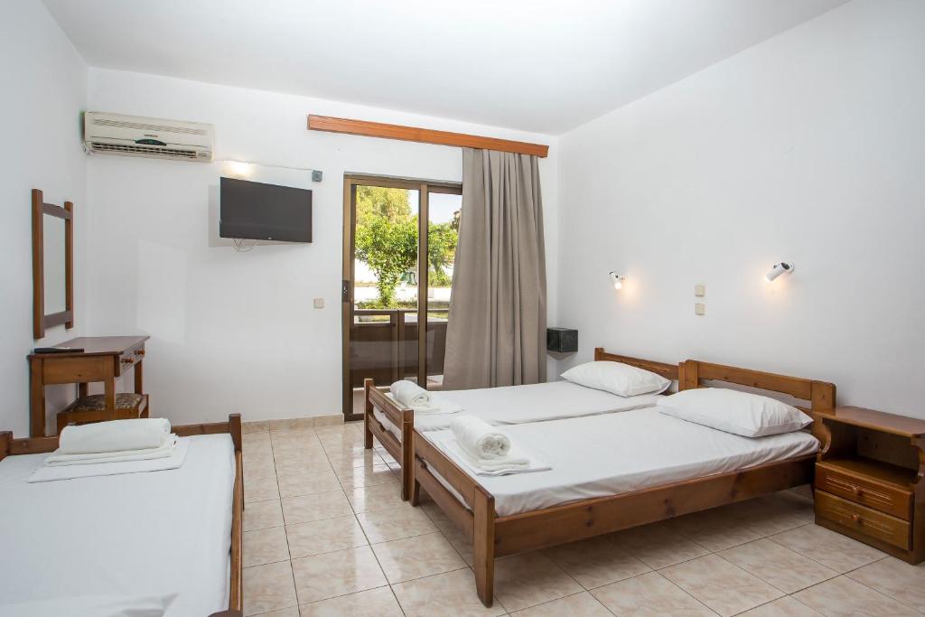 1 dormitorio con 2 camas y TV en la pared en Nikos BnB, en Faliraki