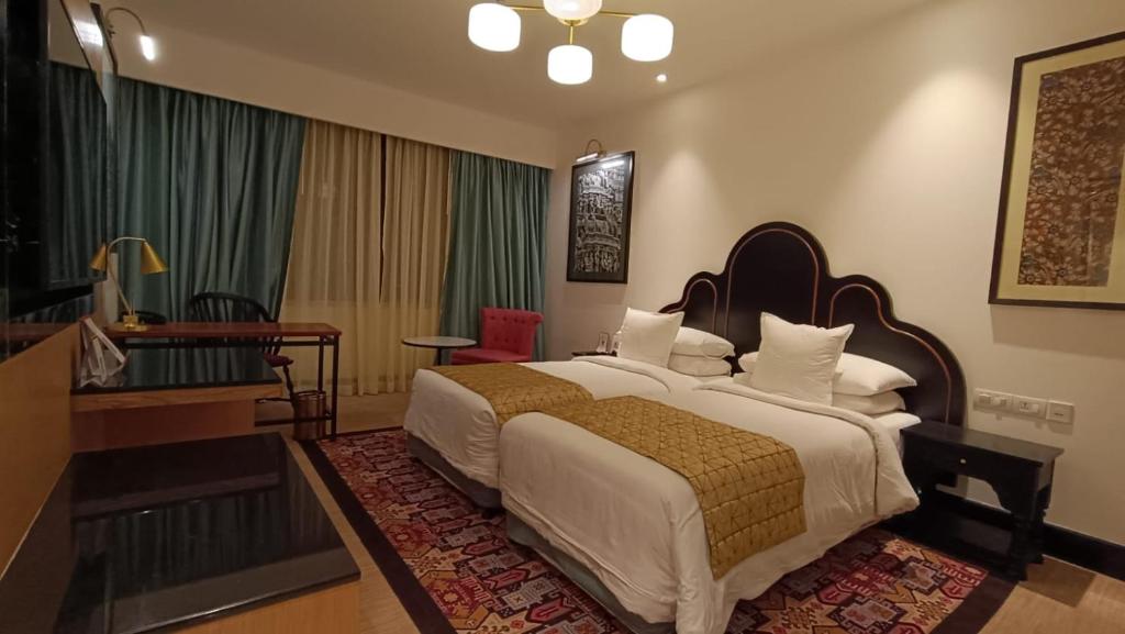 a hotel room with a large bed and a piano at Welcomhotel By ITC Hotels, Guntur in Guntūr