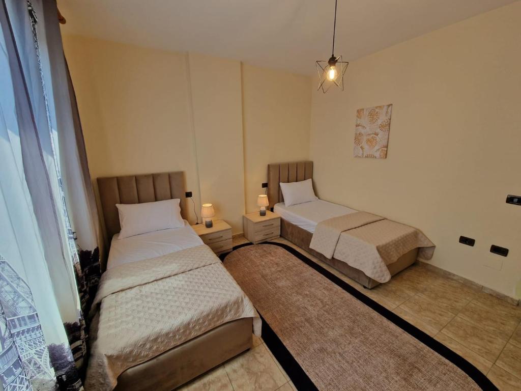 two beds in a small room with two lamps at Donel Apartment in Durrës