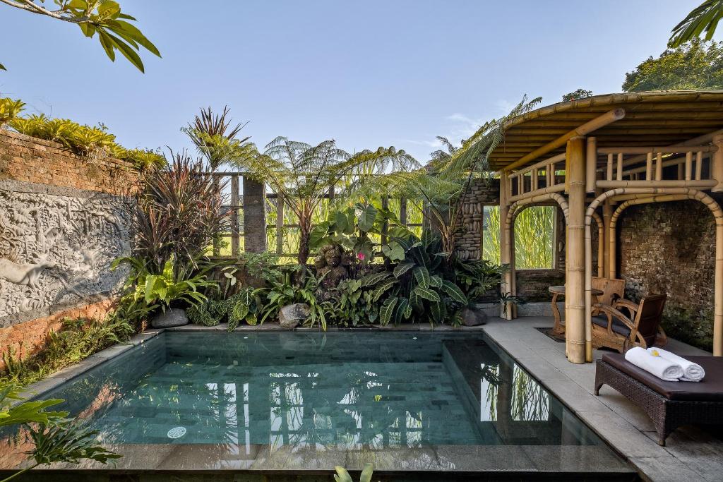 een zwembad in een tuin met een huis bij Roshan Ubud Villa in Ubud