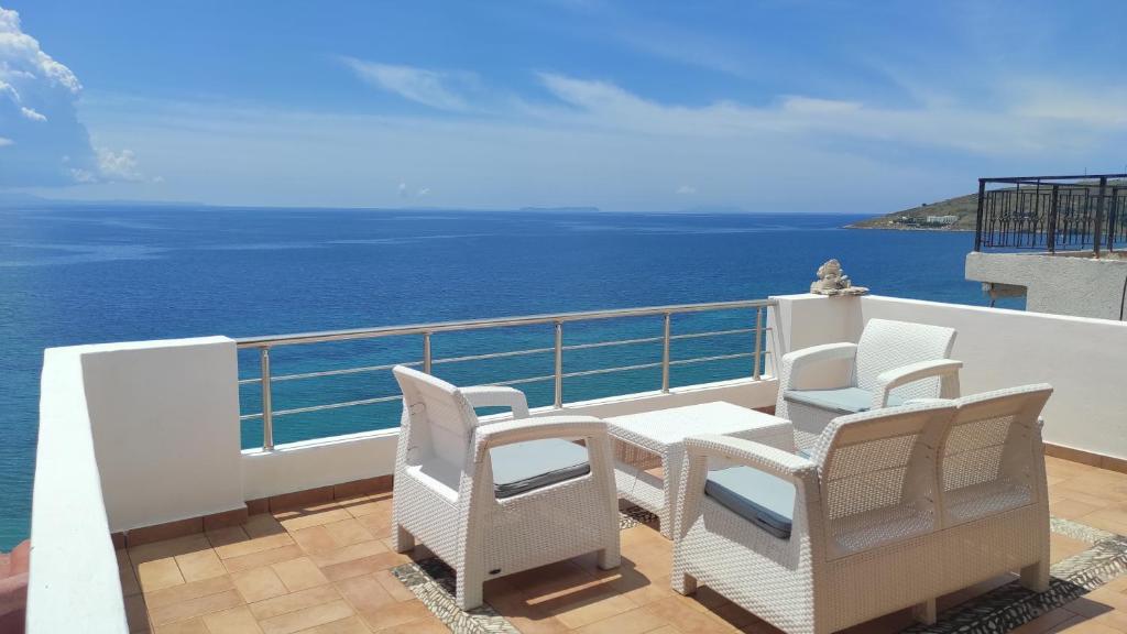 einen Balkon mit Stühlen, einem Tisch und Meerblick in der Unterkunft Q Bay Apartments in Qeparo