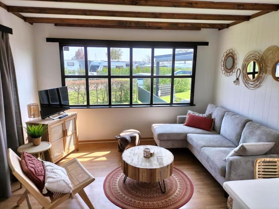 uma sala de estar com um sofá e uma mesa em Chalet Happiness met heerlijk terras en tuin in Kortgene. em Kortgene