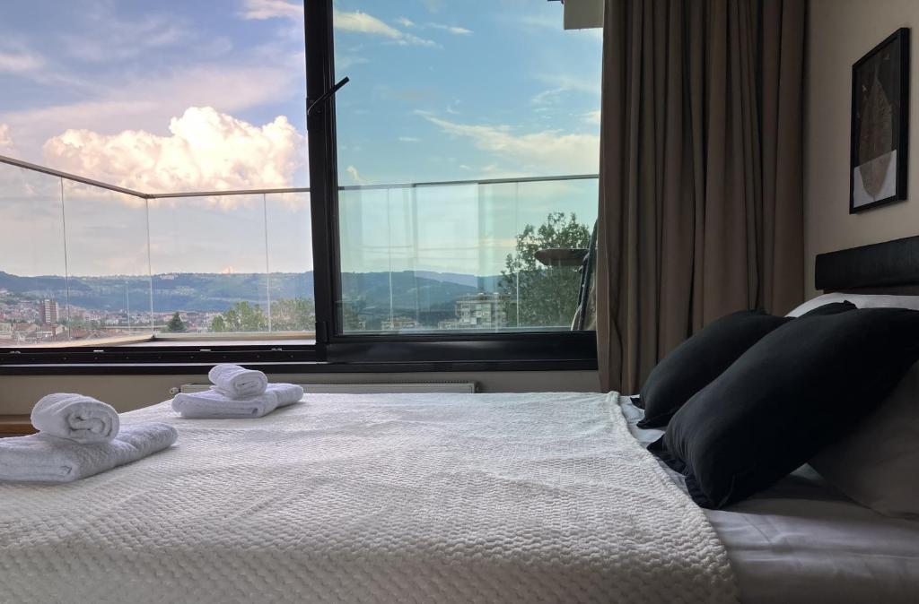 a bedroom with towels on a bed with a large window at Tarnovo Studios City Center in Veliko Tŭrnovo