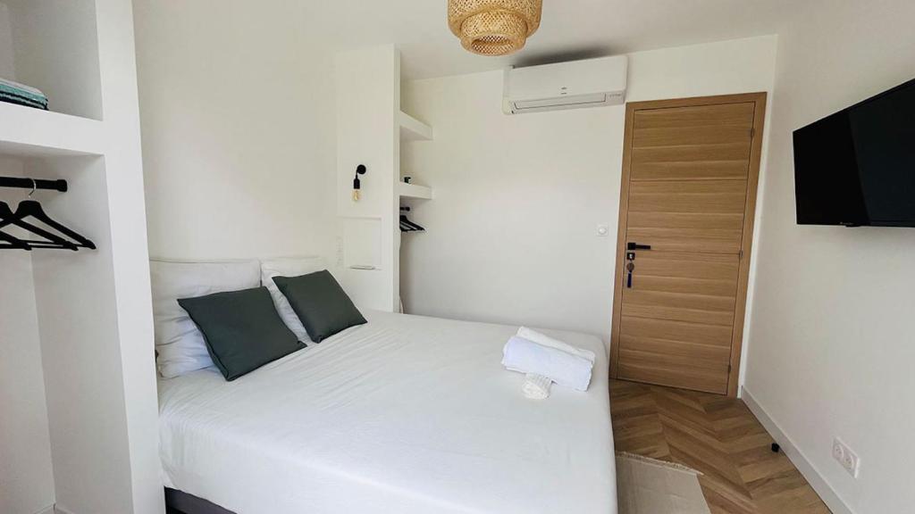 niewielka sypialnia z białym łóżkiem i zielonymi poduszkami w obiekcie VILLA HOLISTIKA : BED AND BREAKFAST / POOL / AIR CONDITIONING/ MONT FARON TOULON w mieście Tulon