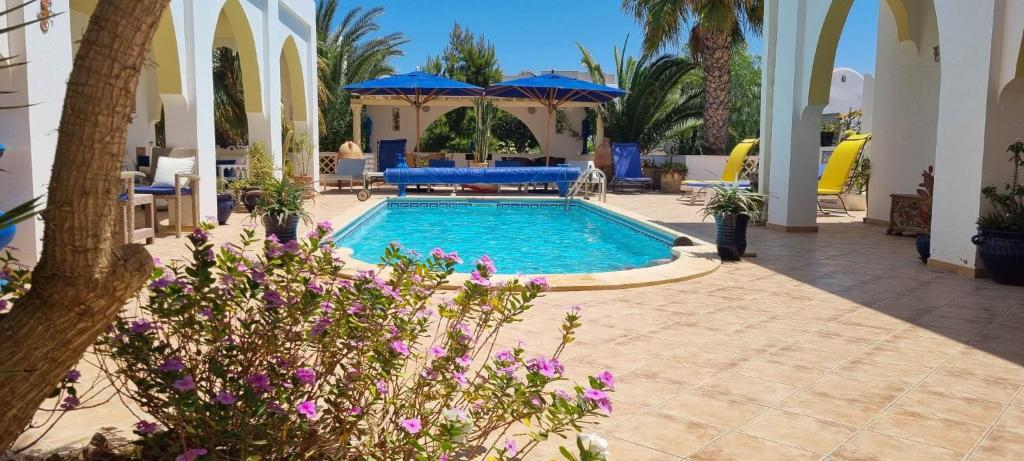 una piscina in un resort con fiori viola di Chambre d'hôtes, Dar l'air du temps ad Aghīr