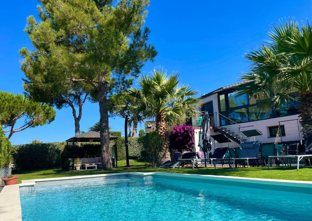 - une piscine en face d'une maison avec des palmiers dans l'établissement L'ESCALE COTE BLEUE VILLA & Spa Classée 4 Étoiles, à Sausset-les-Pins