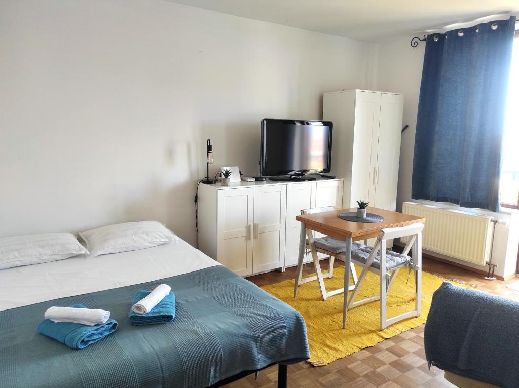 Schlafzimmer mit einem Bett, einem Tisch und einem TV in der Unterkunft Studio Vela in Izola