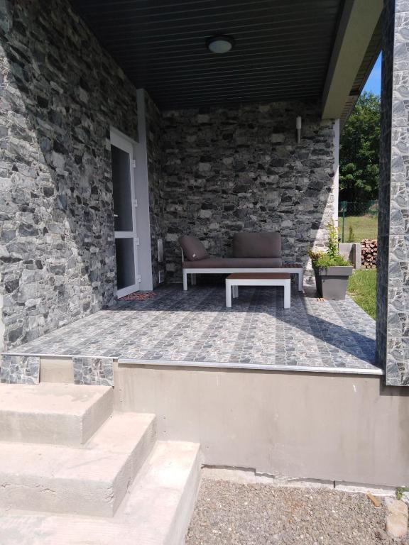 a patio with a bench and a stone wall at Apartmány Vihorlat III in Kaluža