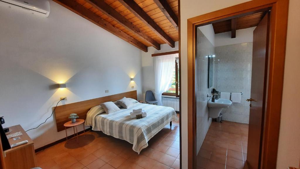 a bedroom with a bed and a bathroom with a sink at Elisa Holidays in Puegnano del Garda
