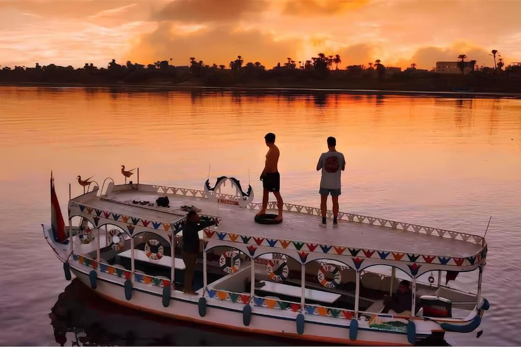 two men standing on a boat in the water at Royal Home Luxor Nile View in Luxor
