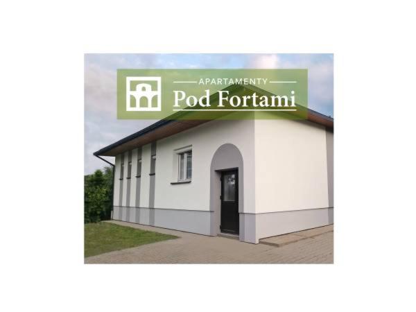a white building with a sign on top of it at Apartamenty Pod Fortami in Przemyśl