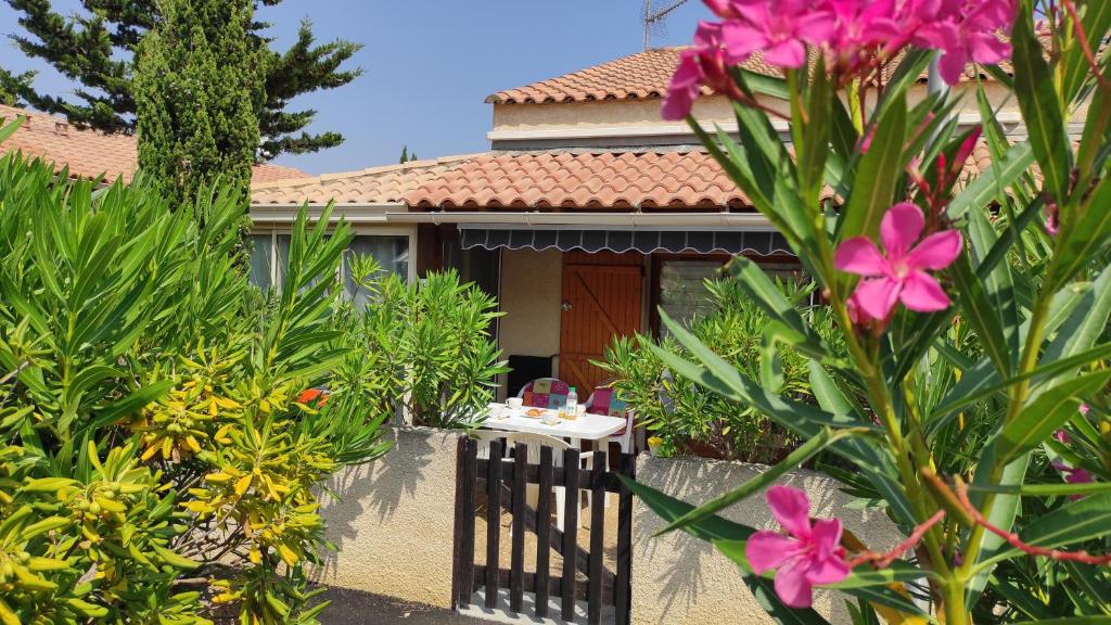 une maison avec une clôture et des fleurs devant elle dans l'établissement maison de vacances climatisée 5 pers avec piscine commune et vélos, à Gruissan
