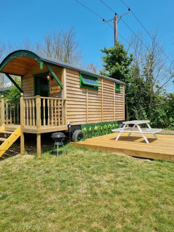 a large wooden cabin with a deck and a swing at Woodie the shepherds hut - sleeps 4 in Chichester