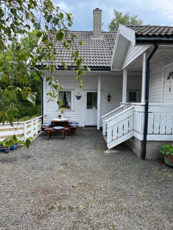 een wit huis met een picknicktafel op de veranda bij Bjørkely gård in Hidra