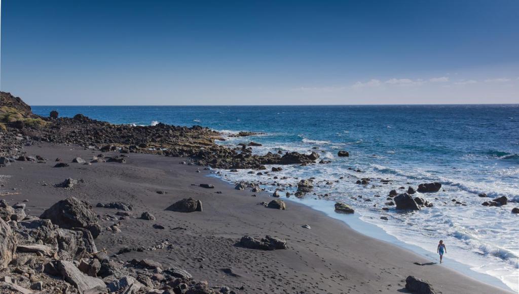 a person standing on a beach near the ocean at Apartamentos Charco del Conde in Valle Gran Rey