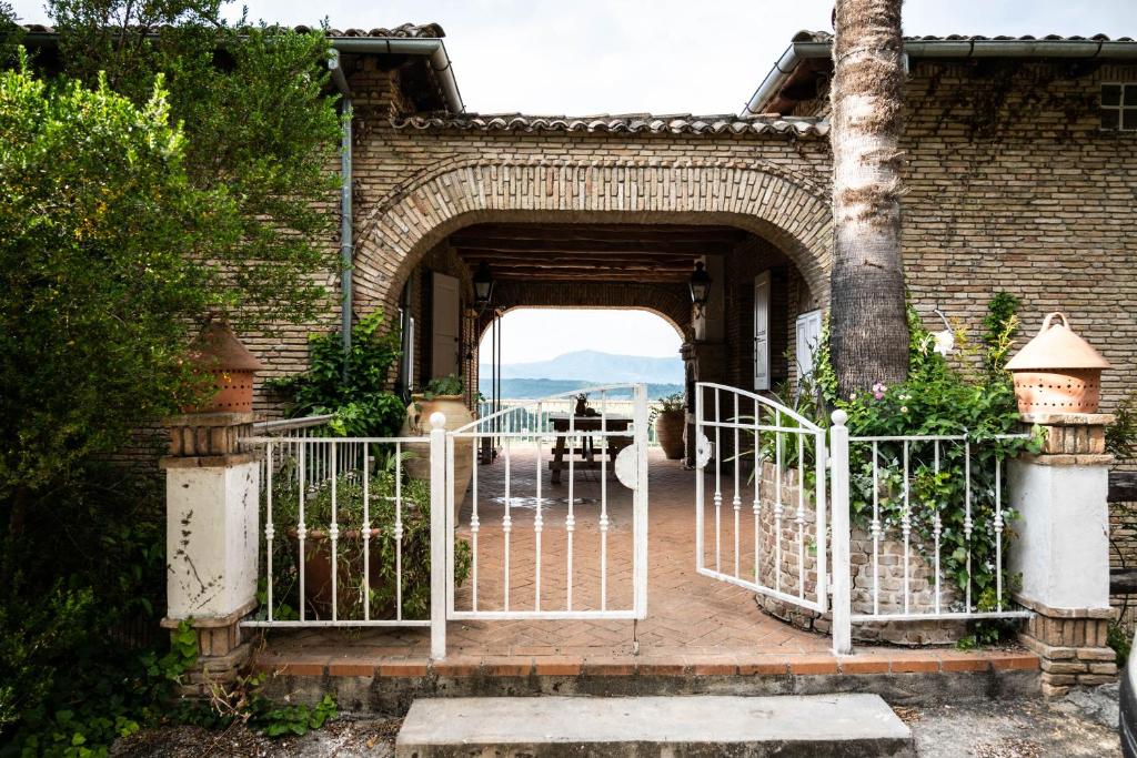 uma entrada para um edifício de tijolos com um portão branco em Guesthouse Elena , Vatos, Corfu em Vátos