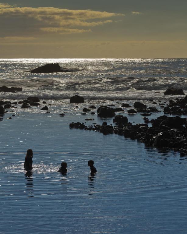 a group of people in the water on the beach at Apartamentos Charco del Conde in Valle Gran Rey