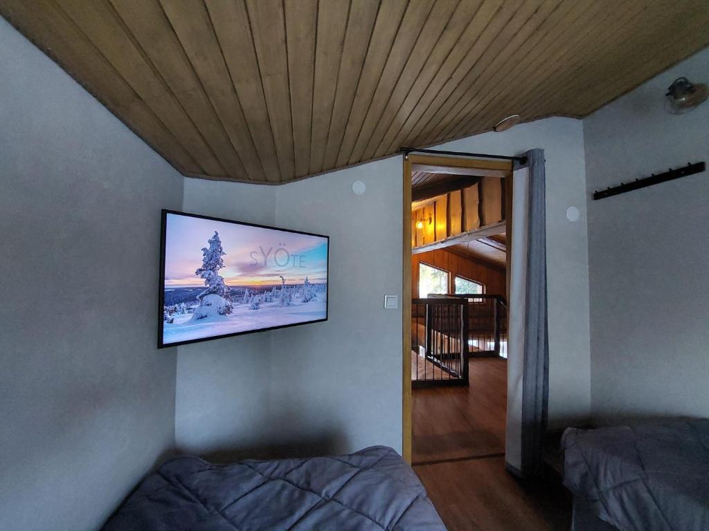 een slaapkamer met een flatscreen-tv aan de muur bij Rovanperän kelomökit in Syöte