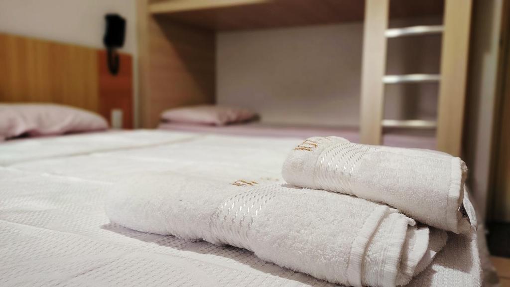 two white towels are stacked on a bed at Flat DiRoma perto do Hot Park in Rio Quente