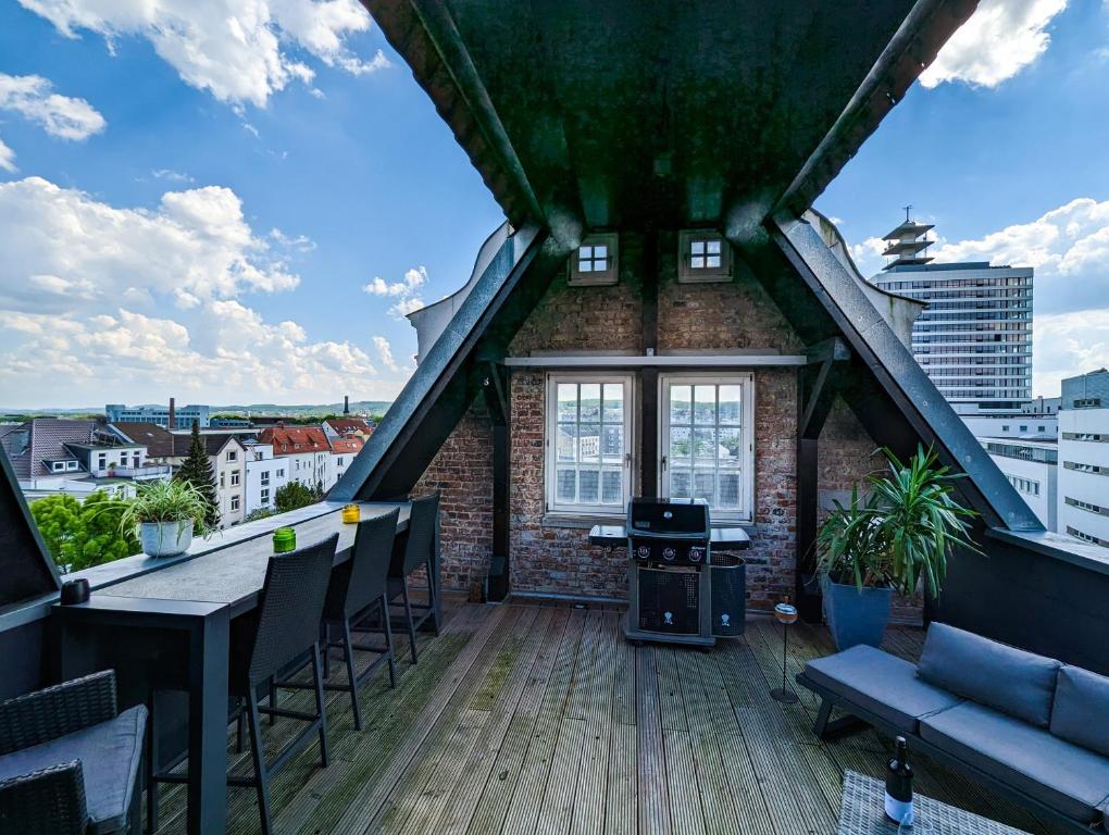 Luxuriöses Penthouse mit Dachterrasse & Massagesessel EM-APARTMENTS DEUTSCHLAND في بيليفيلد: شرفة على طاولة وكراسي في مبنى
