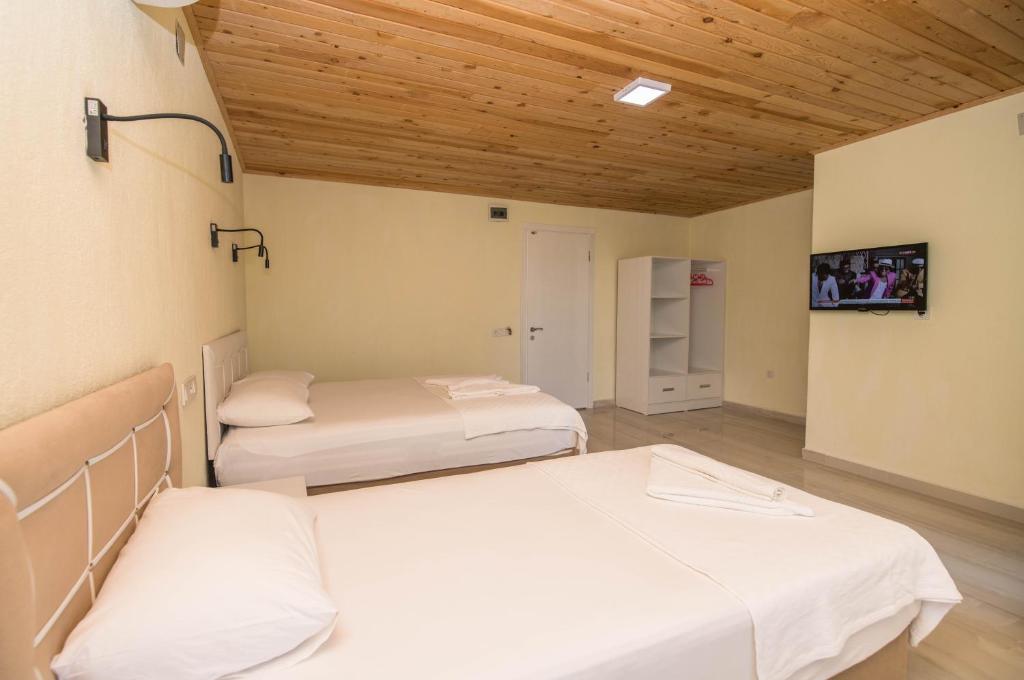 two beds in a room with wooden ceilings at Beyoglu Pansiyon in Patara