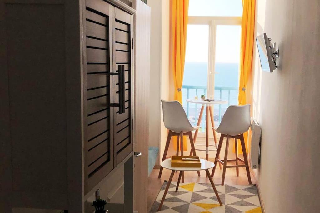 Zimmer mit 2 Stühlen, einem Tisch und einem Fenster in der Unterkunft Studio avec vue mer exceptionnelle sur la plage in Dieppe