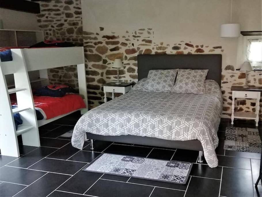 a bedroom with a bed and a stone wall at Gîtes des marais du Lozon - Maison à la campagne in Remilly-sur-Lozon
