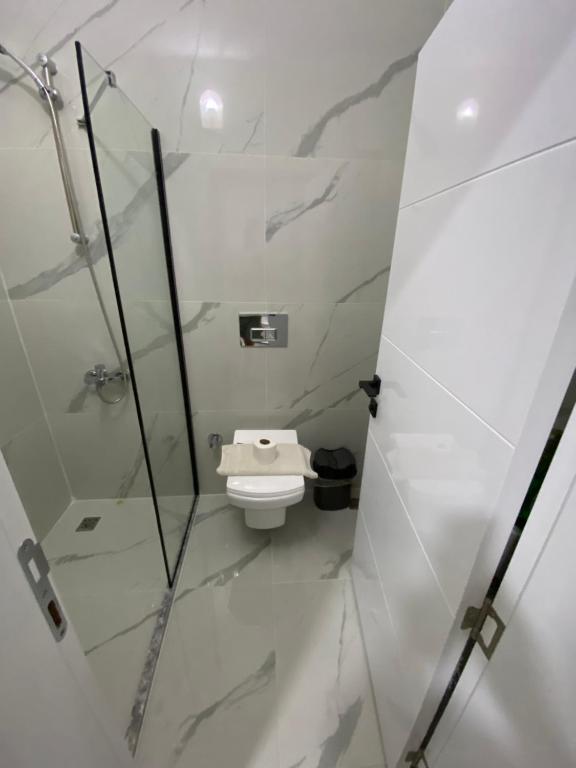 a bathroom with a toilet and a glass shower stall at Beyoglu Pansiyon in Patara