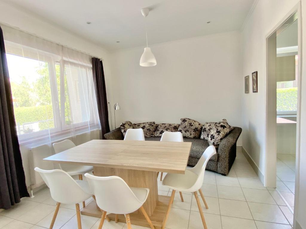 a table and chairs in a living room with a couch at Luca Apartman in Gyenesdiás