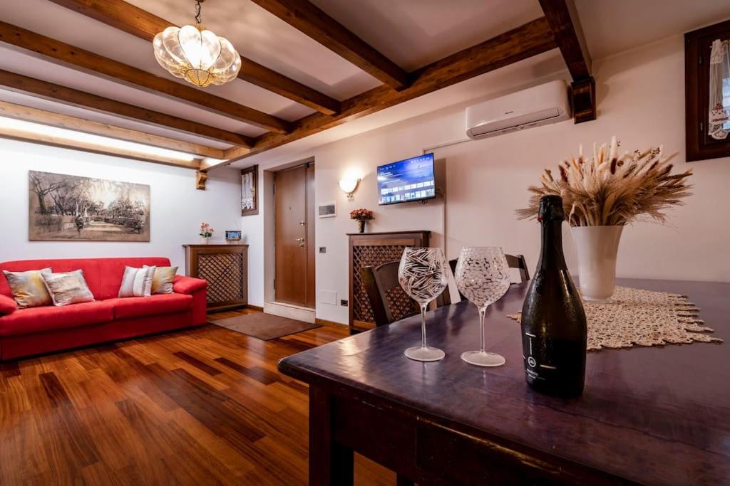 sala de estar con sofá rojo y mesa con copas de vino en Dante's Residence en Venice-Lido