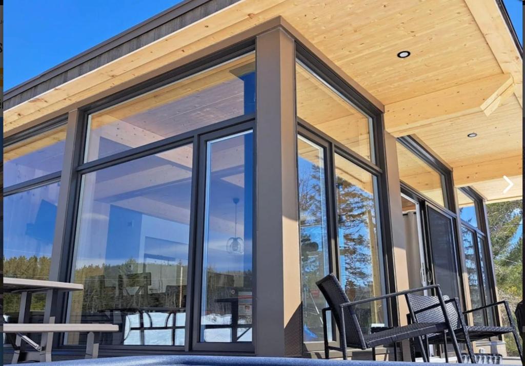 a screened in porch with black chairs and windows at Les Chalets Double K # 2 in Saint-Alexis-des-Monts