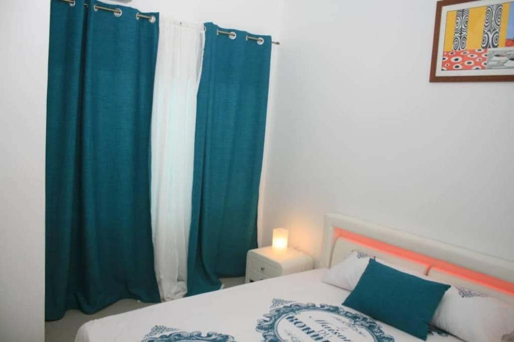 1 dormitorio con cortinas azules y blancas y 1 cama en Bel appartement à Liberté 6 extension, en Dakar