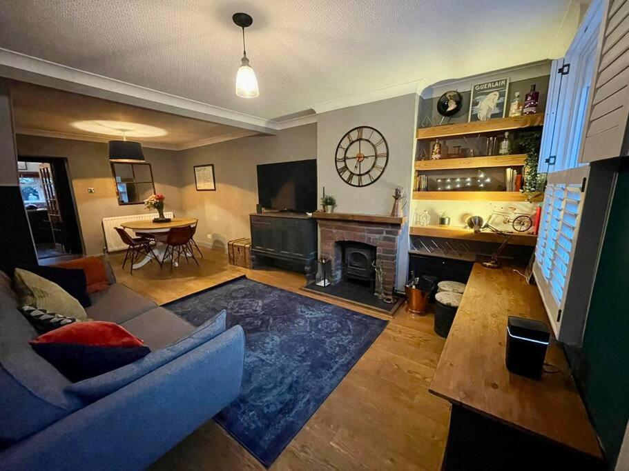 a living room with a couch and a fireplace at 2 bed Victorian Cottage, log burner & garden room. in Dorney