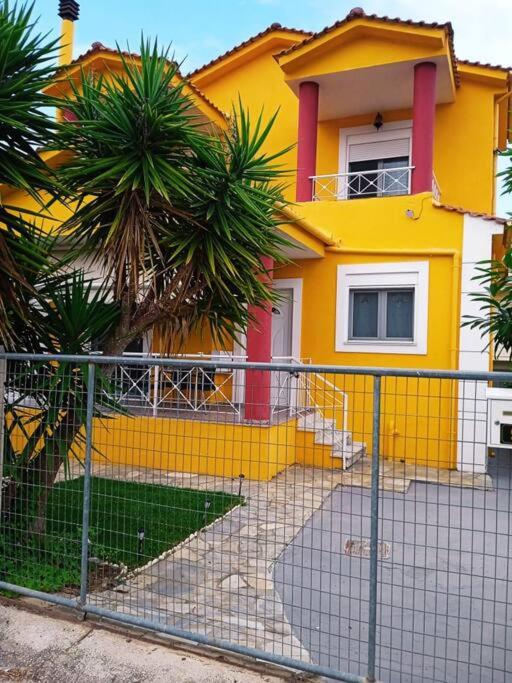 a yellow house with a fence in front of it at The Sunny House in Kritharia