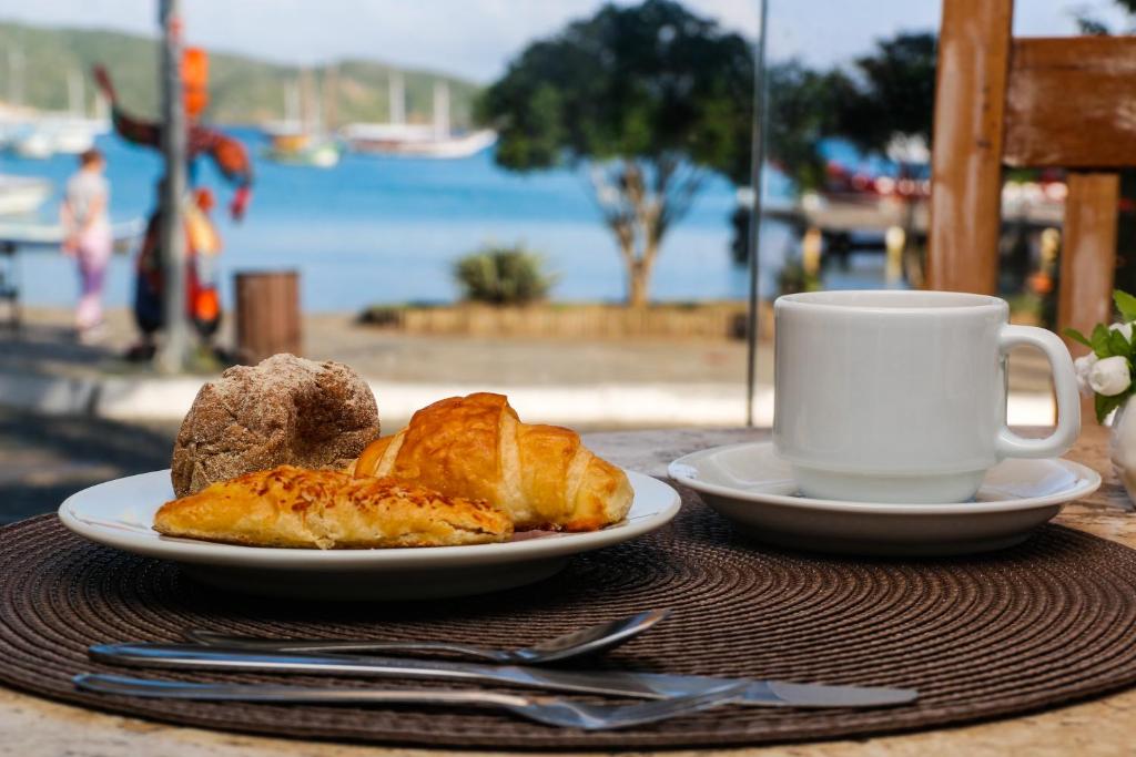 a plate of food and a cup of coffee on a table at Pousada Baía Bonita in Búzios
