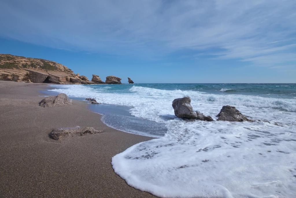 a beach with rocks in the sand and the ocean at Triopetra Luxury Villas Fournou Lago in Triopetra