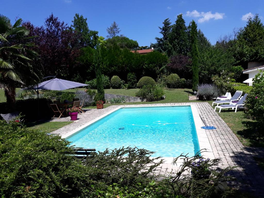 uma piscina num quintal com cadeiras e um guarda-sol em Maison Epellius em Collonges-au-Mont-dʼOr