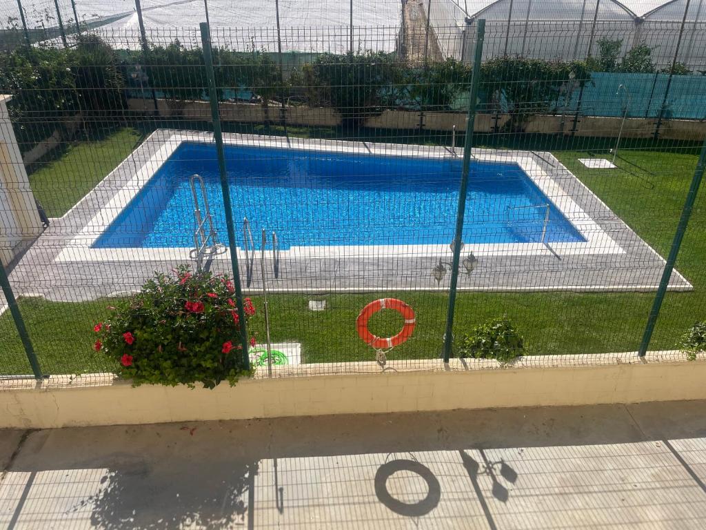 a swimming pool is seen through a fence at Home Chipiona Cadiz Parking in Chipiona