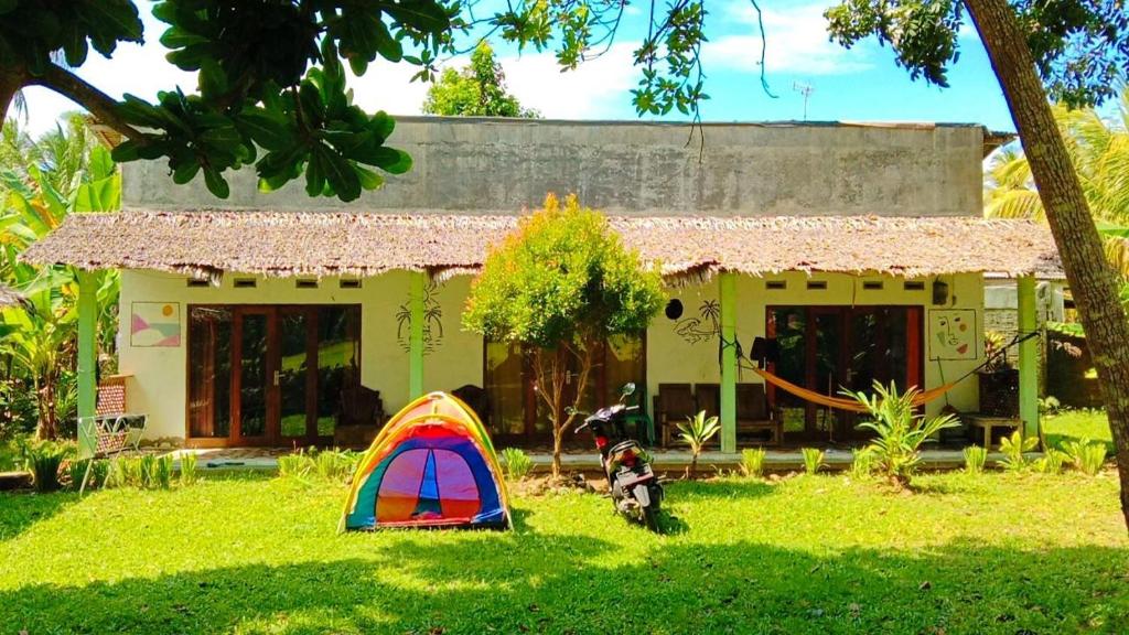 a tent in the grass in front of a house at Susan Homestay in Batukaras