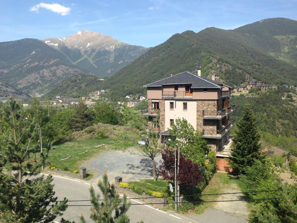 un edificio en una colina con montañas en el fondo en Hotel La Burna Panoràmic en Sispony