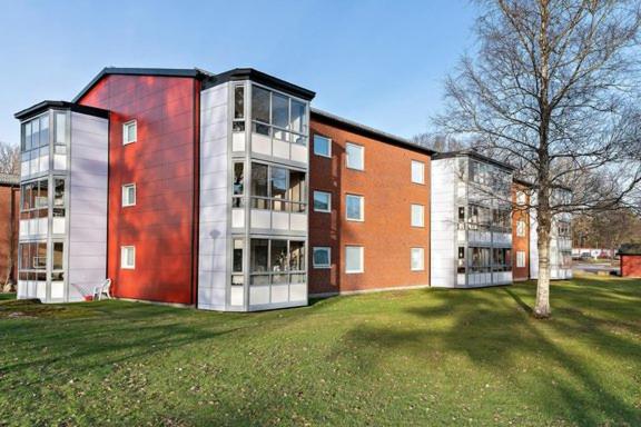 un grand immeuble d'appartements avec une pelouse en face de celui-ci dans l'établissement Rum för övernattning, à Trollhättan