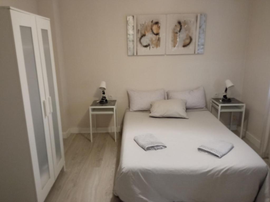 ein Schlafzimmer mit einem weißen Bett und zwei Nachttischen in der Unterkunft PISO PLAZA CABECEO in Jerez de la Frontera