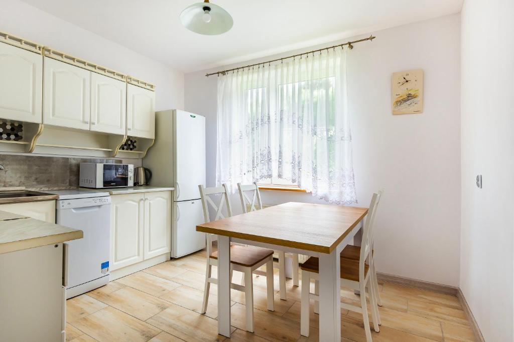eine Küche mit einem Tisch und Stühlen im Zimmer in der Unterkunft VacationClub – Apartament Waryńskiego 14C in Szklarska Poręba