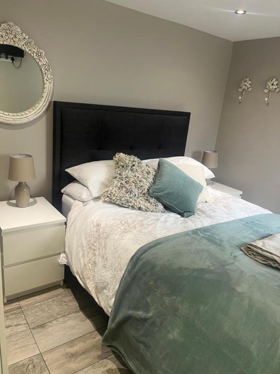 a bedroom with a bed with a black headboard and a mirror at Brand new apartment in Knutsford in Knutsford