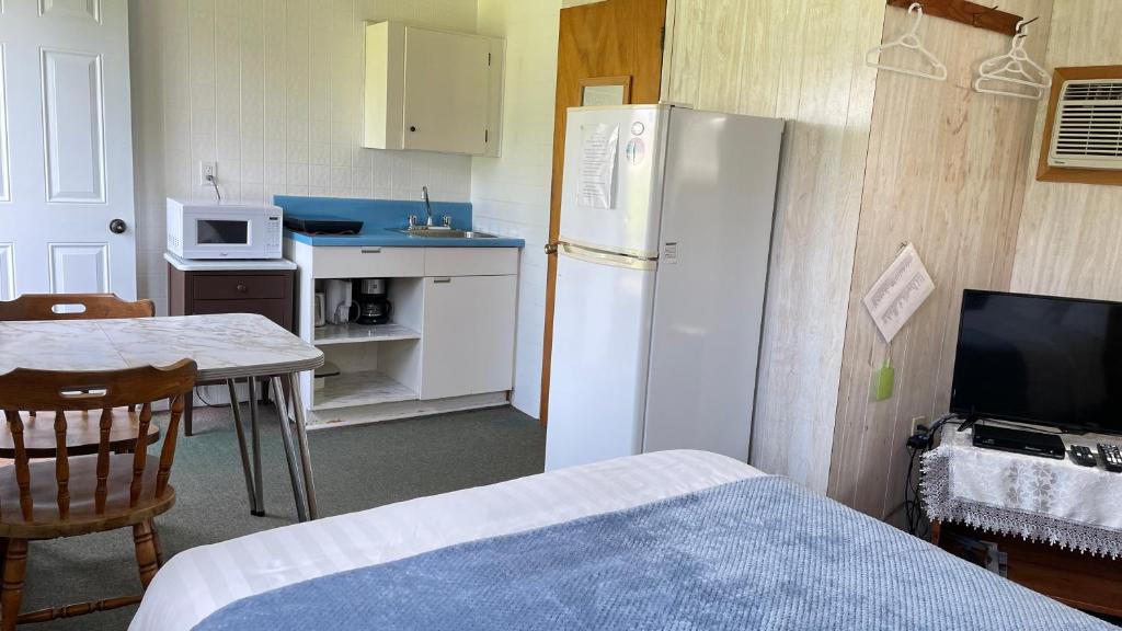 a kitchen with a white refrigerator and a table with a tableablish at Rachel's Motel and Cottages in Surrey