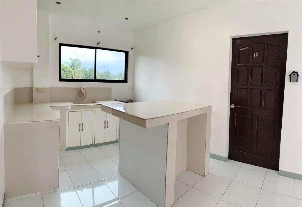 a kitchen with white counters and a window and a door at Luna Oslob Travellers Inn in Oslob