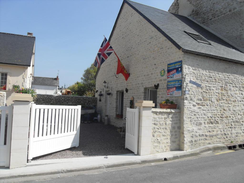a building with a white fence and an american flag at Maison de Pecheur in Port-en-Bessin-Huppain