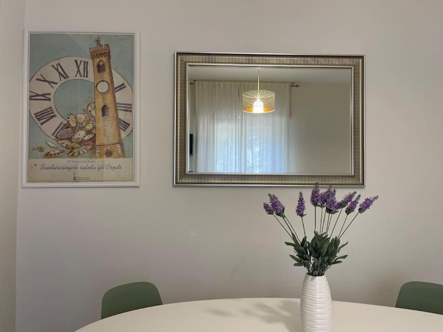 una mesa con un jarrón con flores púrpuras y un espejo en Casetta Mia - Holiday Family House, en Santarcangelo di Romagna